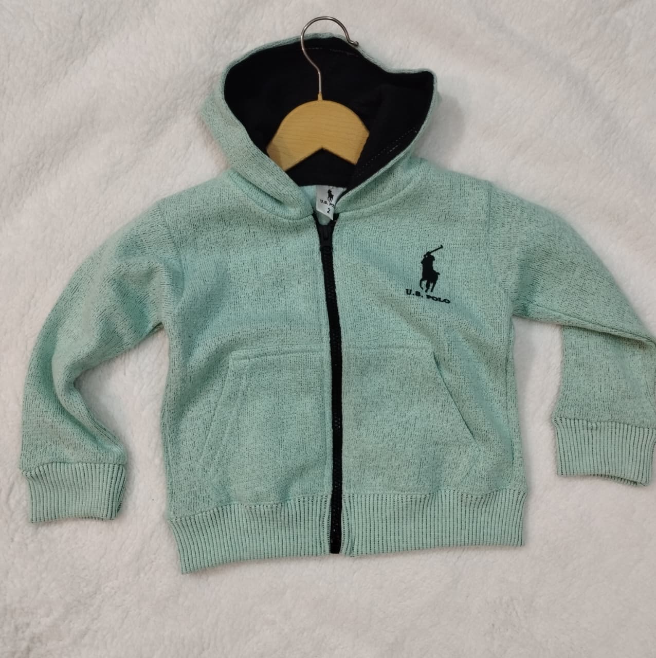 Light green hoodie with a brand logo on a beige background