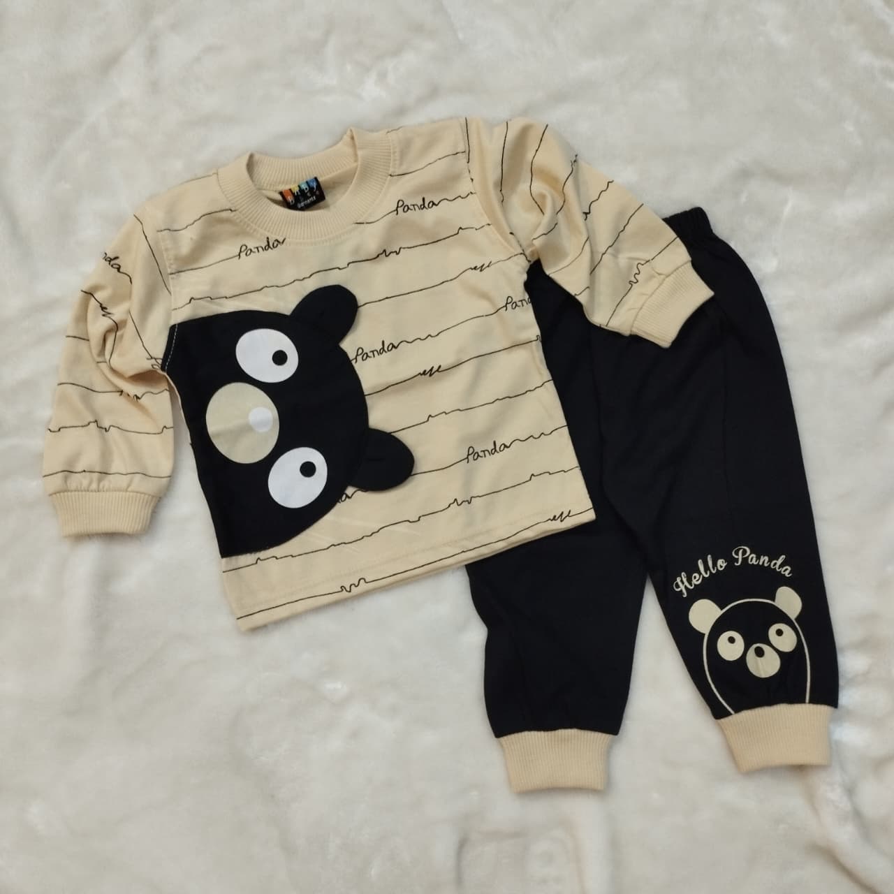 Children's outfit with beige long-sleeve shirt and black pants featuring panda designs on a light gray background.