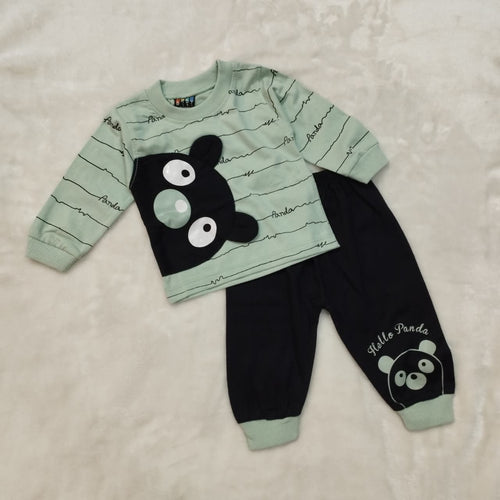 Children's outfit with green top and black pants featuring cartoon face design on a beige background
