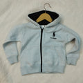 Light blue hoodie with a logo on a beige surface